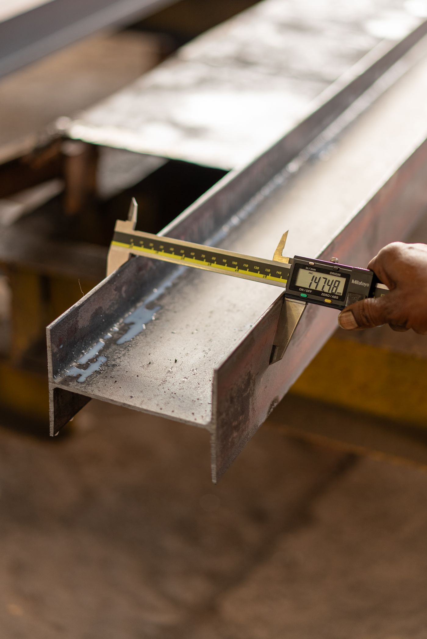 Inspector measuring a steel section with a digital caliper